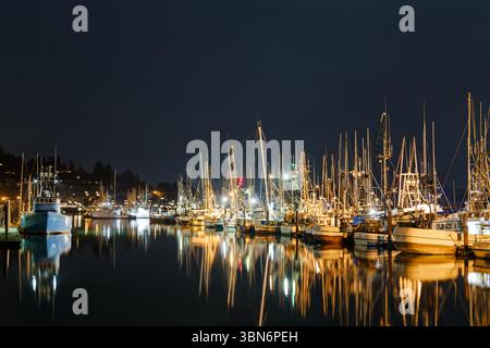 Newport, Oregon, USA - 10. März 2017: Fischerboote legen nachts an, ihre Lichter reflektieren im Wasser. Stockfoto