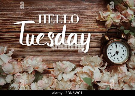 Hallo Tuesday Text mit Wecker und Blumendekoration auf hölzernem Hintergrund Stockfoto