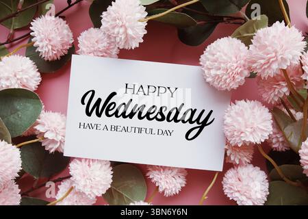 Happy Wednesday habe einen schönen Tag Text mit Blumendekorationen auf rosafarbenem Hintergrund Stockfoto