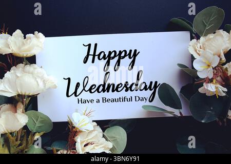 Happy Wednesday haben einen schönen Tag Text mit Blumendekorationen auf schwarzem Hintergrund Stockfoto