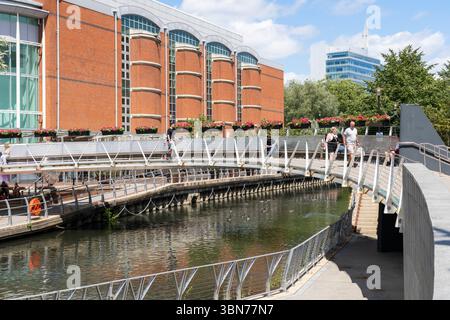 Menschen überqueren eine Fußgängerbrücke über den Kennet River zum Oracle Riverside, einer Fußgängerzone mit Geschäften und Restaurants. Reading, Großbritannien Stockfoto