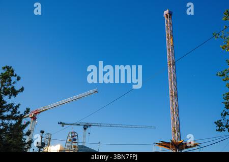 Die Hellevator-Fahrt auf dem Pacific National Exhibition Playland Grounds zusammen mit Kränen für den Bau des neuen PNE Amphitheaters in Vancouver. Stockfoto