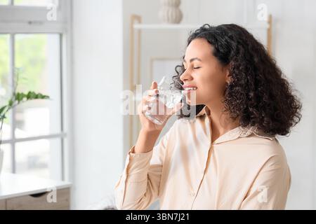 Junge afroamerikanische Frau trinkt zu Hause Wasser Stockfoto
