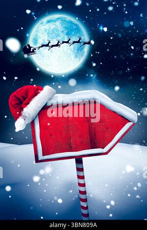 Die flache Designszene zeigt ein rotes Schild mit Weihnachtsmütze unter der Silhouette eines Mondscheinschlittens, Kopierraum Stockfoto