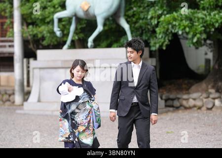 Im Juni 2025 schlendert ein junges japanisches Paar Anfang 20 durch das friedliche Gelände eines Shinto-Schreins und trägt dabei sein einmonatiges Ba Stockfoto