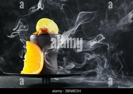 Shisha Schüssel mit Zitrusfrüchten und Rauch auf schwarzem Tisch, Nahaufnahme Stockfoto