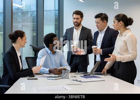 Eine vielfältige Gruppe von Geschäftsleuten in einer modernen Büroumgebung, die mit einem Laptop und Dokumenten auf einem Tisch an einem Meeting teilnahmen. Stockfoto