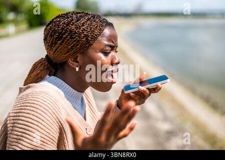 Die junge schwarze Frau spricht am Telefon. Sie ist ängstlich und besorgt. Stockfoto