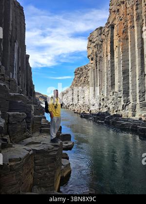Bewundern Sie die atemberaubenden Basaltsäulen, die über dem ruhigen Wasser des Studlagil Canyon in Island thronen. Dieses geologische Wunder lädt Besucher ein, seine beeindruckende Landschaft zu erleben. Stockfoto