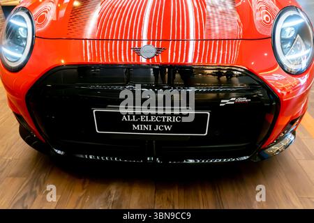 Die Vorderseite eines roten Mini JCW mit dem Schild „All Electric Mini JCW“ in einem Ausstellungsraum Stockfoto
