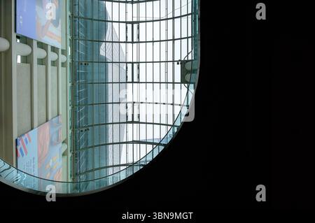 Der Blick durch eine kreisförmige Innenöffnung im Eaton Centre zeigt die geschwungene Glasdecke, die vertikalen Balken und die große hängende Werbung in der Nähe des Hotels Stockfoto