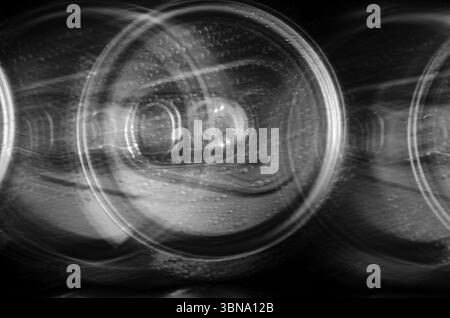 Abstrakte Nahaufnahme mehrerer Getränkedosen in Bewegung vor schwarzem Hintergrund. Stockfoto