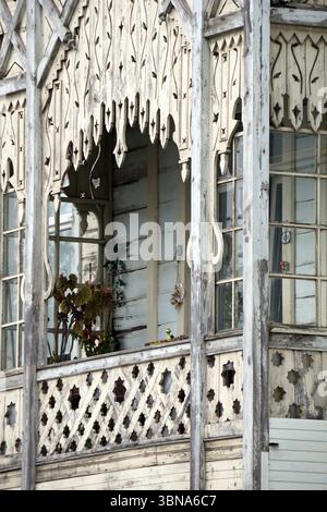 Ein verwittertes Holzgebäude mit einer weißen oder cremefarbenen Fassade. Das Gebäude verfügt über einen Balkon mit einem gitterartigen Muster und einen dekorativen Bogengang darüber. Der Balkon hat ein kleines Pflanzen- oder Blumenarrangement. Das Äußere des Gebäudes besteht hauptsächlich aus weißem oder cremefarbenem Holz, wobei einige Bereiche Alterserscheinungen und Abnutzungserscheinungen aufweisen. Die Fenster sind mit komplizierten Schnitzereien verziert, was den Charme des Gebäudes noch verstärkt. Das Design des Gebäudes erinnert an traditionelle oder historische Architektur. Ein Künstlerauge und fantasievolle Unterschrift., Istanbul, Türkei. Die größte Stadt der Türkei und eine der Stockfoto