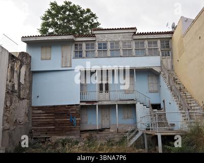 Verwitterte hellblaue Holzfassade eines verlassenen Hauses in den Straßen von Athen, die Zeichen von Alter und Verfall zeigt. Stockfoto