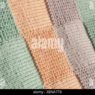 Handgefertigte Winterdecke aus Wollgarn in Pfirsichfarben, Mintgrün und Lavendelfarben. Die perfekte Textur des Materials zeigt unterschiedliche Schlaufenmuster Stockfoto
