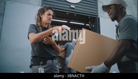 Verschiedene Mitarbeiter, die Kartons zum Logistics Distribution Warehouse transportieren. Weibliche Manager scannt Pakete mit Barcode-Scanner mit Digital Tablet. Online-Bestellungen, Lieferung, E-Commerce-Waren. Stockfoto