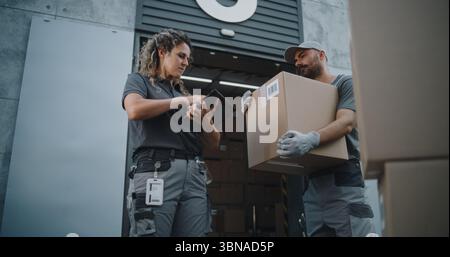 Multiethnische Mitarbeiter bringen Kartons mit Online-Bestellungen, E-Commerce-Waren zum Logistics Retail Warehouse. Weibliche Inventory Manager scannt Pakete mit Barcode-Scanner mit Tablet-Computer. Stockfoto