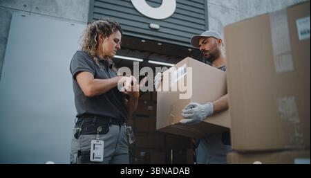 Verschiedene Mitarbeiter, die Kartons zum Logistiklager transportieren. Weibliche Koordinatorin scannt Pakete mit Barcode-Scanner mit digitalem Tablet. Online-Bestellungen, Lieferungen und E-Commerce-Waren. Stockfoto