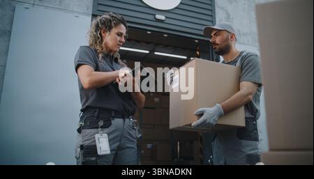 Verschiedene Mitarbeiter, die Kartons zum Logistics Distribution Warehouse transportieren. Weibliche Manager scannt Pakete mit Barcode-Scanner mit Digital Tablet. Online-Bestellungen, Lieferung, E-Commerce-Waren. Stockfoto