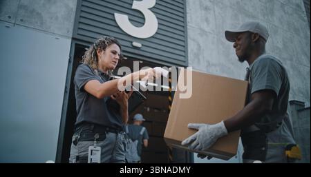 Verschiedene Mitarbeiter, die Kartons zum Logistics Distribution Warehouse transportieren. Weibliche Manager scannt Pakete mit Barcode-Scanner mit Digital Tablet. Online-Bestellungen, Lieferung, E-Commerce-Waren. Stockfoto