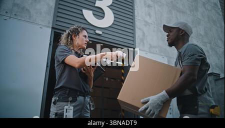 Verschiedene Mitarbeiter, die Kartons zum Logistics Distribution Warehouse transportieren. Weibliche Manager scannt Pakete mit Barcode-Scanner mit Digital Tablet. Online-Bestellungen, Lieferung, E-Commerce-Waren. Stockfoto