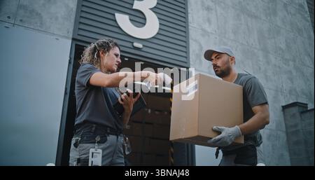 Verschiedene Mitarbeiter, die Kartons zum Logistics Distribution Warehouse transportieren. Weibliche Manager scannt Pakete mit Barcode-Scanner mit Digital Tablet. Online-Bestellungen, Lieferung, E-Commerce-Waren. Stockfoto