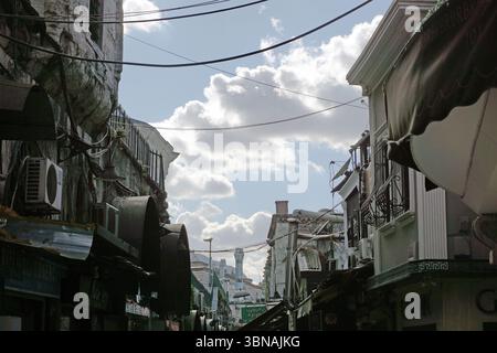 Istanbul, Türkei. Die größte Stadt in der Türkei und eine der wenigen transkontinentalen Städte der Welt, die sich über Europa und Asien erstreckt, über die enge Straße des Bosporus, Eine Mischung aus alten und neuen architektonischen Stilen. Die Straße ist von Gebäuden gesäumt, von denen einige mit Markisen und Balkonen verziert sind, andere mit Markisen, die aus Wellblech bestehen. Die Gebäude sind hauptsächlich in Grau- und Weißtönen gehalten, einige mit Balkonen und Markisen. Die Straße ist mit einer Vielzahl von Geschäften und Geschäften gefüllt, und die Gebäude sind dicht zusammengepackt. Stromleitungen Stockfoto