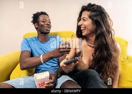 Ein authentischer Moment, in dem ein glückliches junges Paar zusammen lacht, während er zu Hause einen Comedy-Film ansieht. Stockfoto