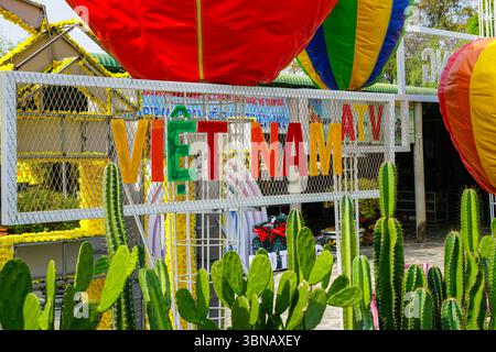 Mui ne, Vietnam – 21. März 2025: Ein lebhaftes VIETNAM-Schild hebt sich zwischen bunten Ballons und hohen grünen Kakteen bei der festlichen Bau Trang-Ausstellung hervor Stockfoto