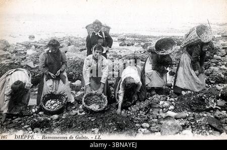 Sieben Frauen sammeln Kies am felsigen Ufer von Dieppe, jede mit einem Korb in der Hand. In traditioneller Arbeitskleidung schlüpfen sie entlang der Gezeitenlinie. Die Szene mit dem Titel Ramasseuses de Galets fängt die Küstenarbeit des frühen 20. Jahrhunderts mit ruhiger, rhythmischer würde ein. Veröffentlicht um 1910 von Léon & Lévy. Von einer Originalpostkarte. Stockfoto
