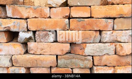 Orangene Backsteinmauerstruktur eines ruinösen Gebäudes. Teil einer alten Mauer, gelbes Mauerwerk aus Steinblöcken als Hintergrund Stockfoto