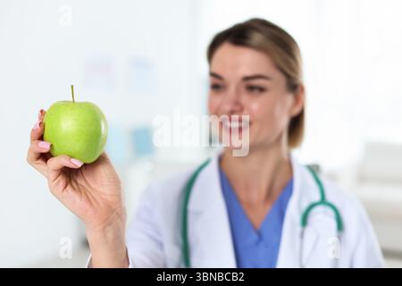 Ernährungswissenschaftler mit grünem Apfel und Stethoskop in der Klinik, selektiver Fokus Stockfoto