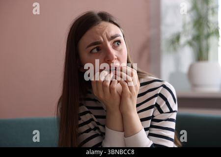 Verängstigte Frau, die zu Hause an Paranoia leidet Stockfoto