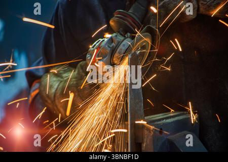 Winkelschleifer und Funken, Metallarbeiter schleifen ein Stück Metall Stockfoto