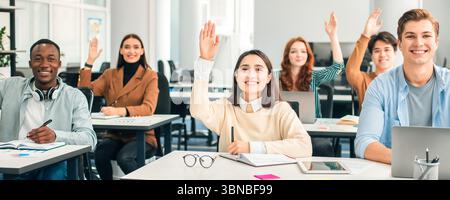 Porträt von verschiedenen Schülern, die im Klassenzimmer die Hände heben Stockfoto