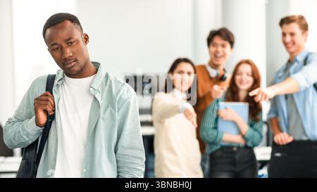 Die Leute spotten und machen sich über den traurigen afrikanischen Mann lustig Stockfoto