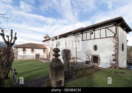 Traditionelle baskische Kirche mit Fachwerkarchitektur, eingebettet in eine ruhige Landschaft mit gepflegtem Rasen Stockfoto