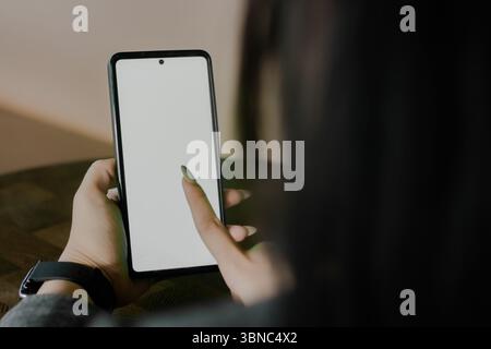 Die Hand einer Frau interagiert mit einem Smartphone und zeigt den leeren Bildschirm mit einem einfachen Fingertipp. Ideal zur Demonstration der App-Nutzung und Moderne Stockfoto