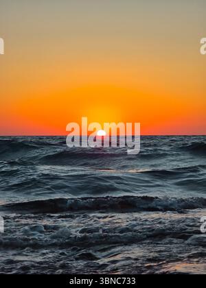 Malerischer Blick auf das Meer vor dem orangefarbenen Himmel. Blick auf das Meer bei Sonnenuntergang Stockfoto