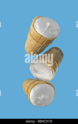Eis in Waffelbechern fliegen auf blauem Hintergrund Stockfoto