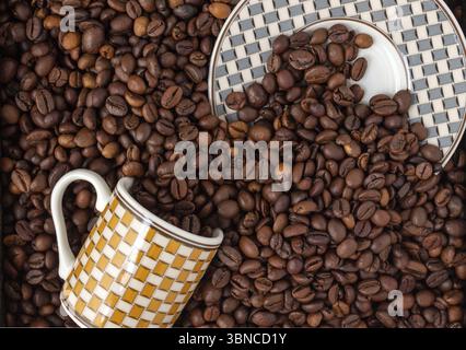 Tasse und Untertasse in Kaffeebohnen vergraben, selektiver Fokus Stockfoto