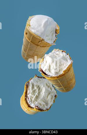 Gebissenes Eis in Waffelbechern fliegt auf blauem Hintergrund Stockfoto