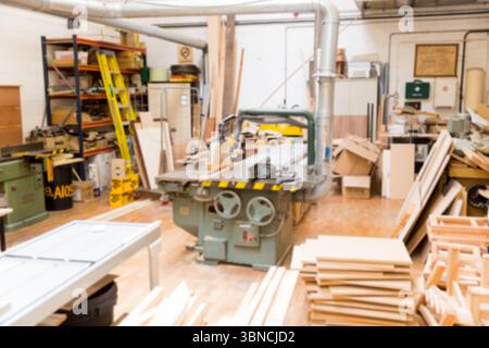 Die flache Bauweise zeigt grüne Tischsäge und Holzbretter in der Werkstatt mit Staubschutzrohren Stockfoto