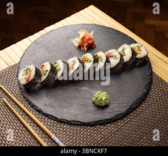 Köstliche vegane Sushi-Brötchen mit Gemüse auf einem schwarzen Schieferteller Stockfoto