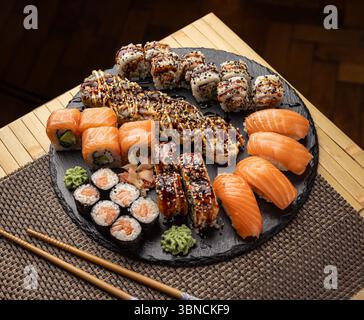 Köstliche Sushi-Mischung mit verschiedenen Arten von Brötchen, serviert mit Sojasauce, eingelegtem Ingwer und Wasabi Stockfoto