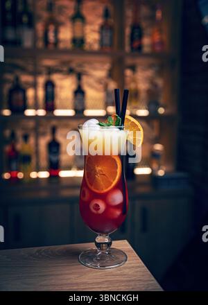 Erfrischender Cocktail garniert mit Minz- und Orangenscheiben, serviert in einem Hurrikanglas an einer Bar Stockfoto