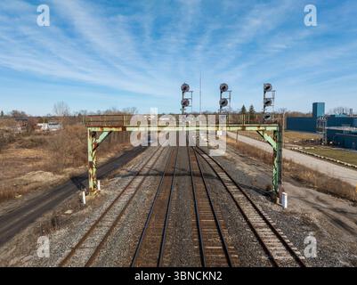 Ein Blick aus der Vogelperspektive über einem 4-gleisigen Eisenbahnsystem mit Blick auf die Ampelleuchten über dem Gleis an einem Tag mit blauem Himmel. Stockfoto