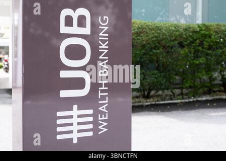 Penang, Malaysia – 15. April 2025: Ein großes Schild für UOB Wealth Banking befindet sich in der Nähe von grünen Hecken und einem sauberen Bürgersteig, was auf einen Finanzdienstleister hinweist Stockfoto