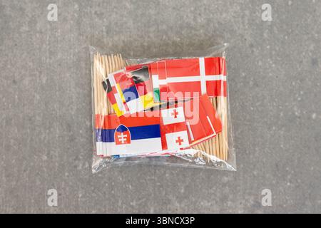 Plastiktüte mit Zahnstocher-Flaggen auf grauem Hintergrund Stockfoto