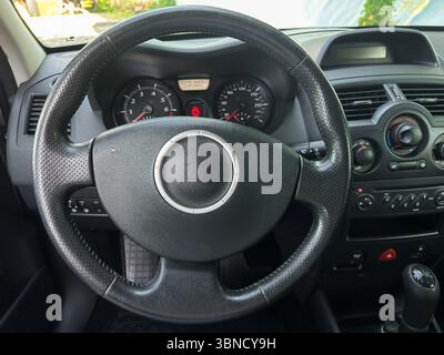 Die Nahaufnahme eines modernen, schlanken Lenkrads unterstreicht das komplizierte Armaturenbrett-Design und die innovativen Bedienelemente, die sich ideal für Fahrzeugbilder und in Fahrzeugen eignen Stockfoto